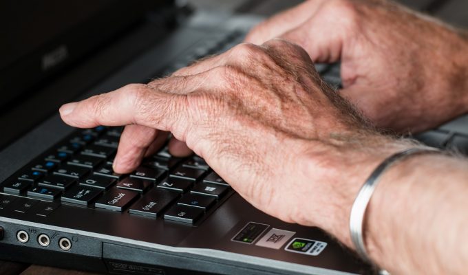 elderly hands typing on computer